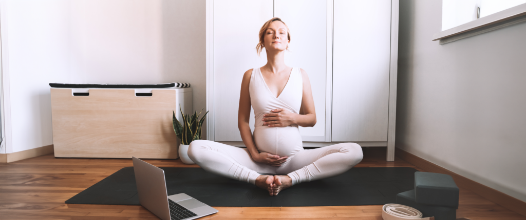 Frain Yogapose streichelt ihren Babybauch.
